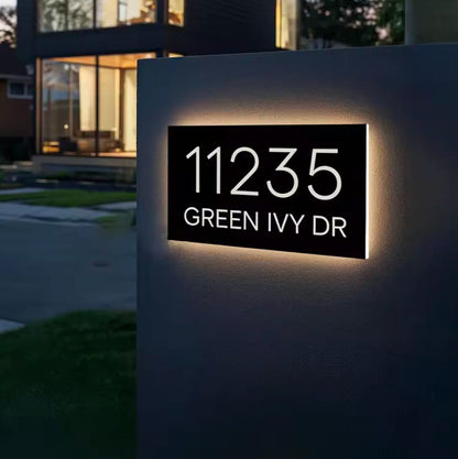 Custom warm white LED rectangular house address sign illuminated on an outdoor pillar at night