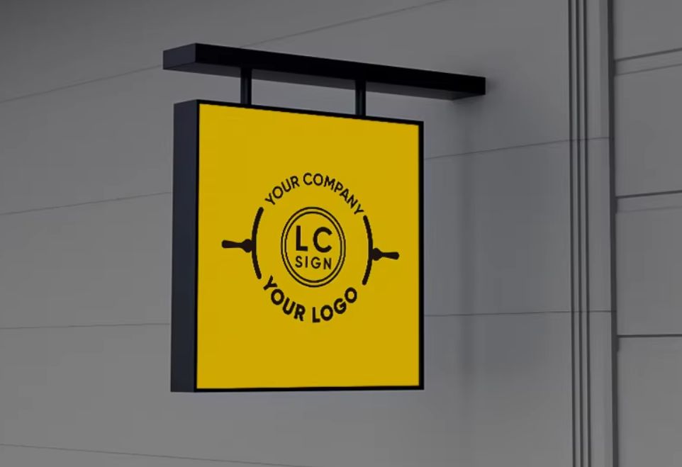 Custom double-sided acrylic LED business lightbox sign in yellow with black logo mounted on building exterior.