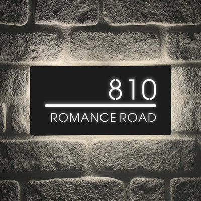 Custom LED house number sign 810 Romance Road mounted on brick wall with illuminated white lettering.