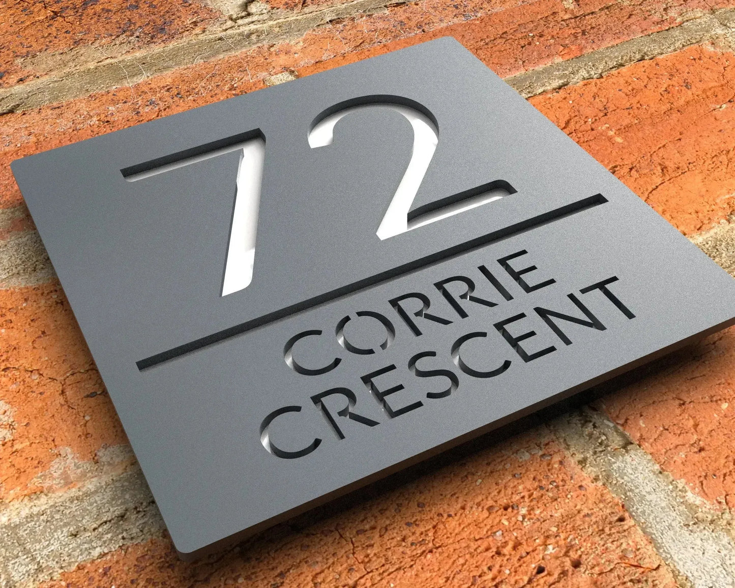 Square custom acrylic house sign with number 72 and Corrie Crescent text mounted on brick wall