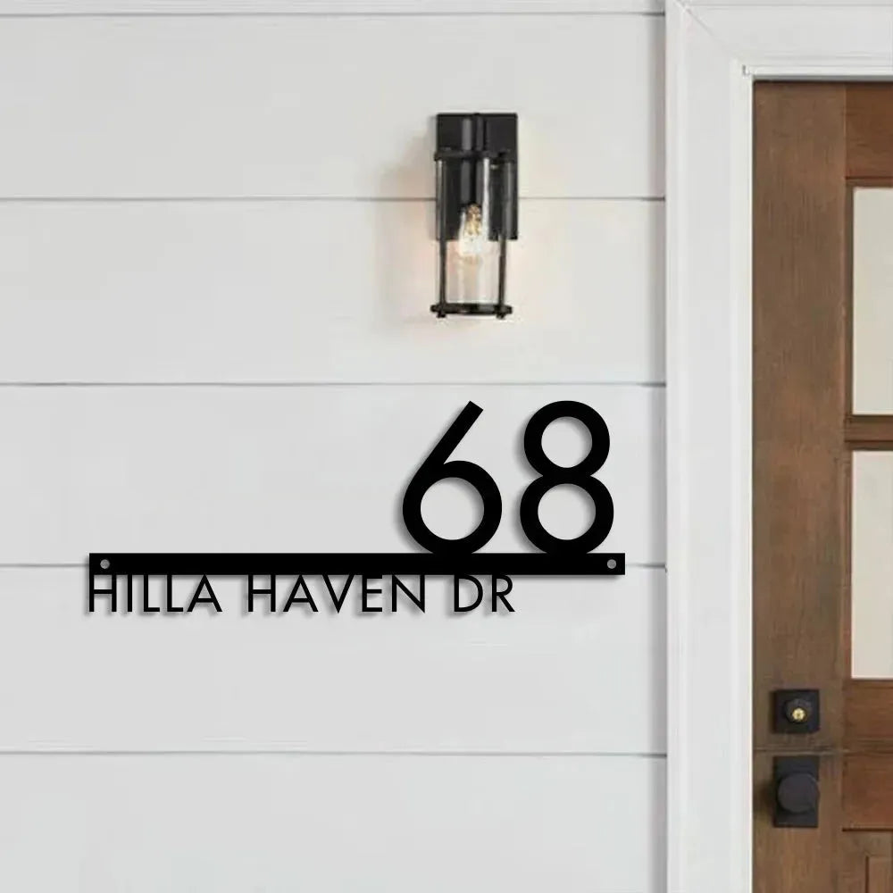 Custom modern floating house number plaque with black raised numbers and address on white shiplap siding near wooden door.