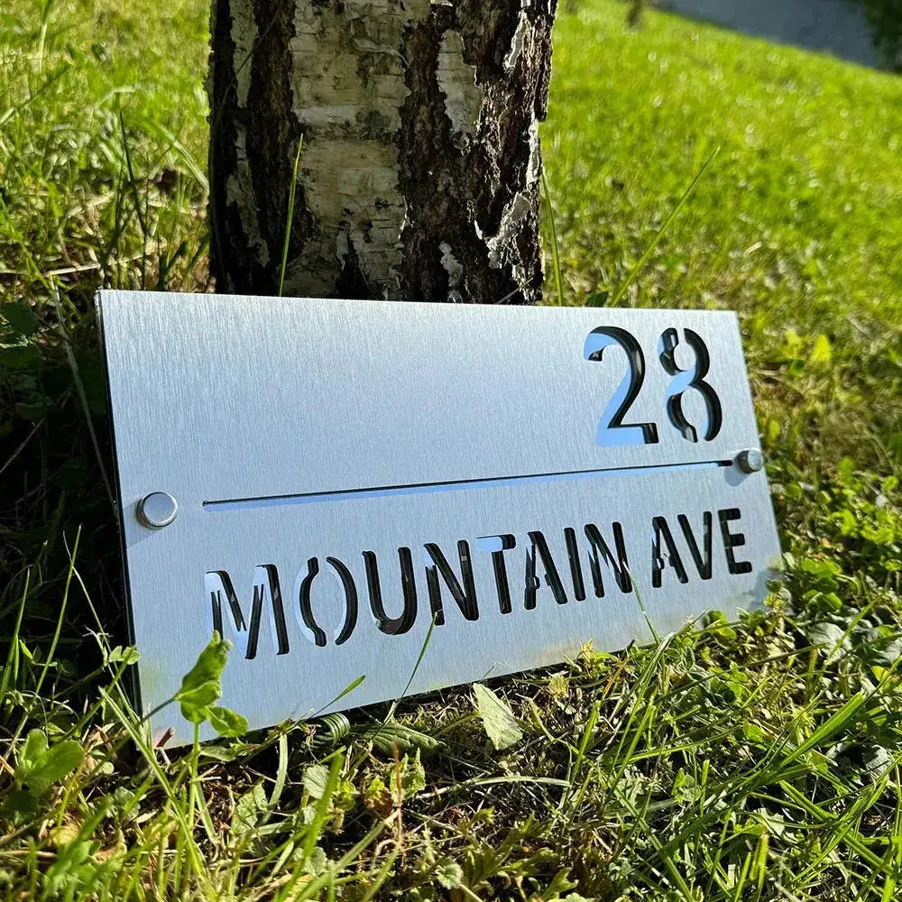 Personalised stainless steel address sign with custom cut-out numbers and street name for outdoor display.