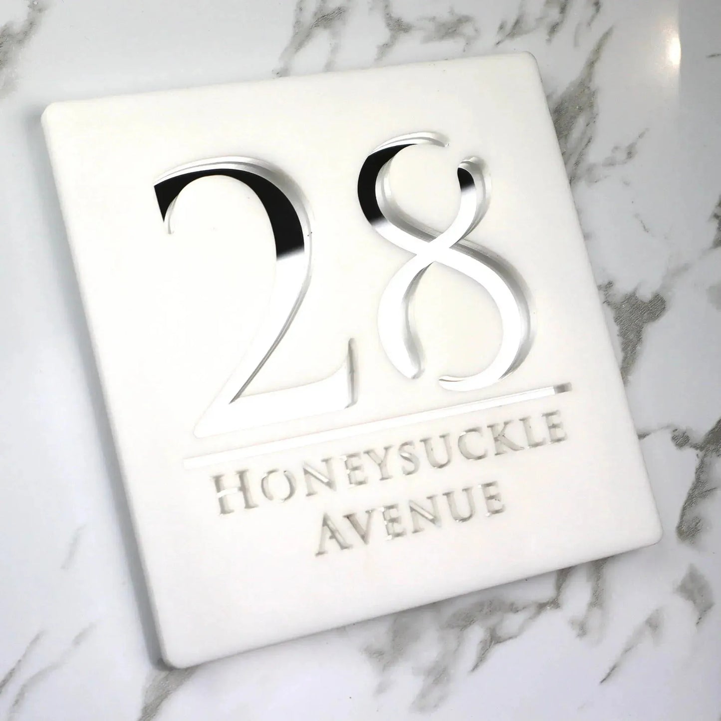 Custom square acrylic house number sign with raised numbers and street name on white marble background
