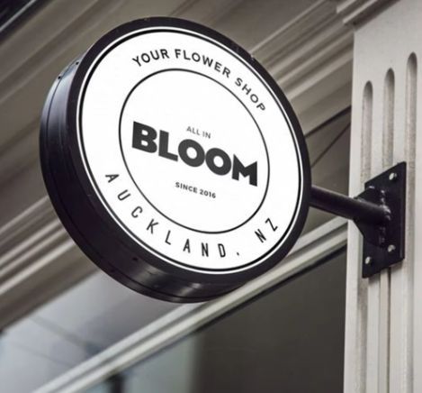 Round double-sided business signage lightbox mounted on a building exterior for a flower shop.