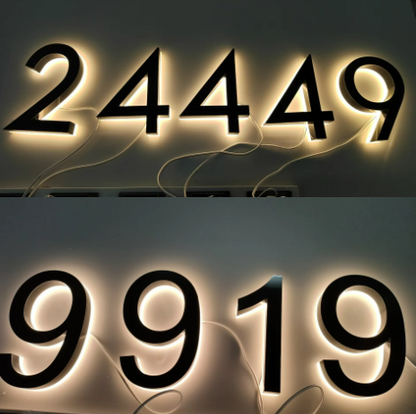 Matte black custom metal LED house numbers glowing softly with visible wiring against a dark background.