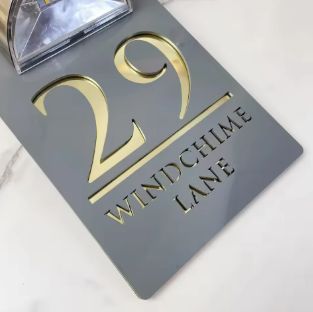 Custom solar-powered acrylic house sign with gold engraved numbers and address on a gray rectangular panel