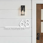 Custom modern floating house number plaque with raised white numbers and street name on grey shiplap siding next to wooden door