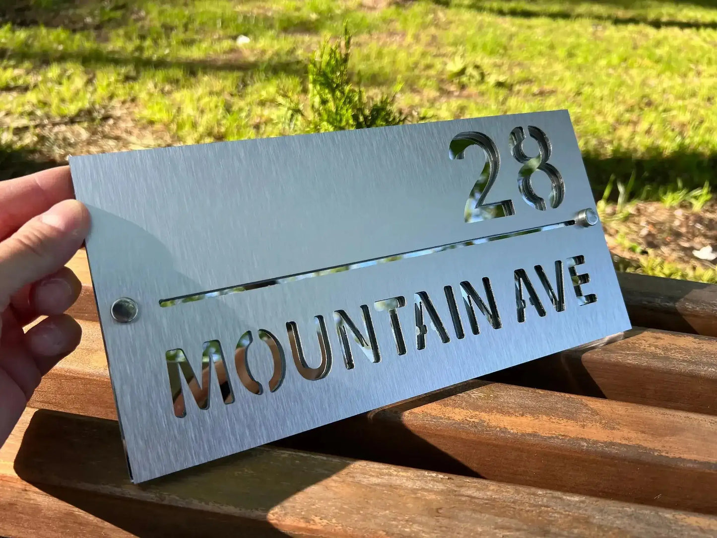Handheld personalised stainless steel address sign with brushed finish showing number 28 and Mountain Ave text