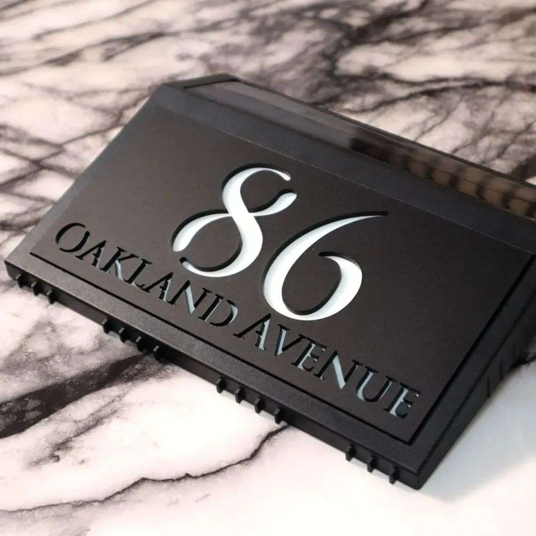 Modern black solar acrylic house sign with illuminated number 86 and Oakland Avenue address engraving.